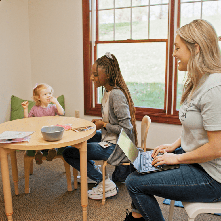 Two BlueSprig employees sitting and looking at a child