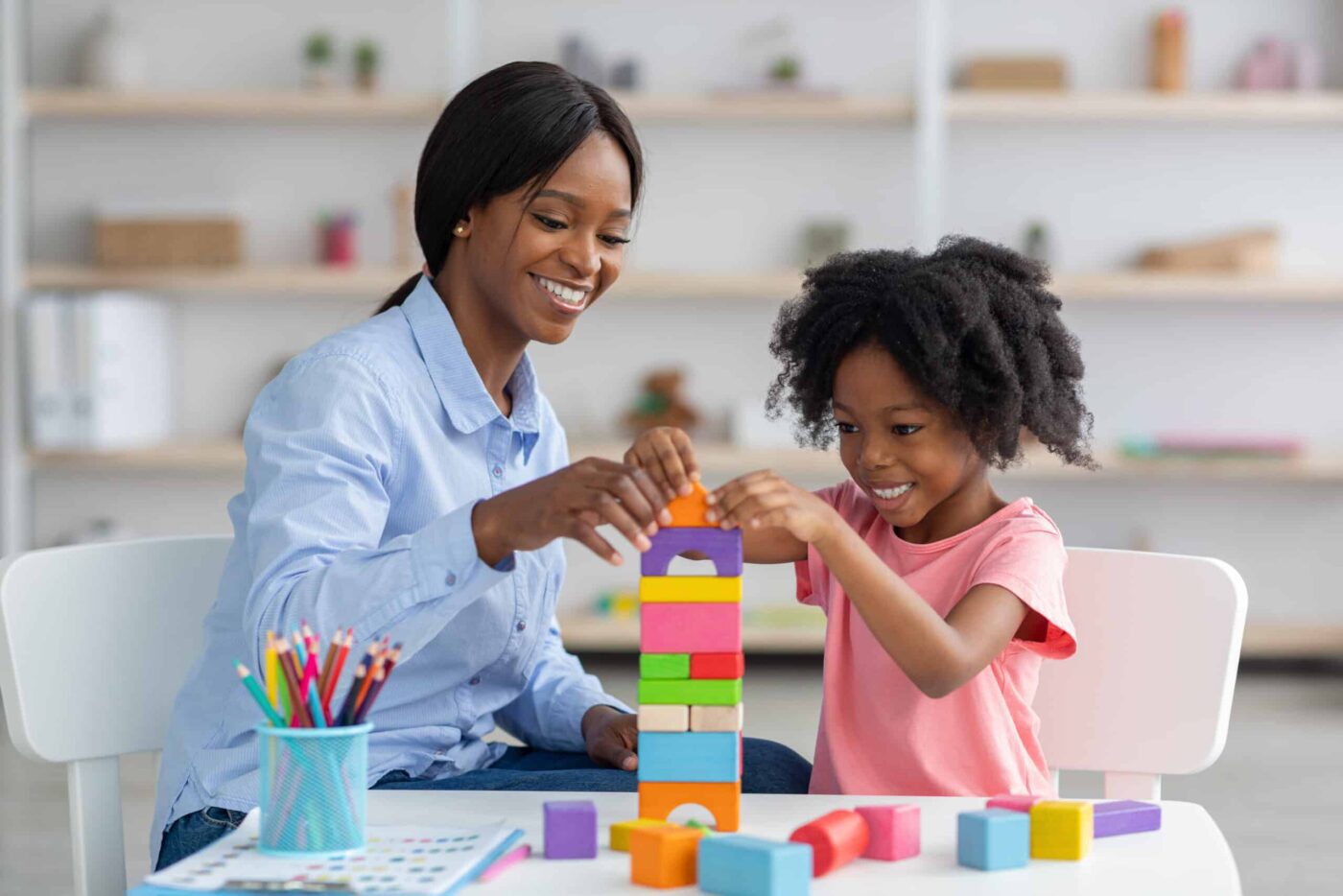 An ABA therapist plays with a client with blocks.