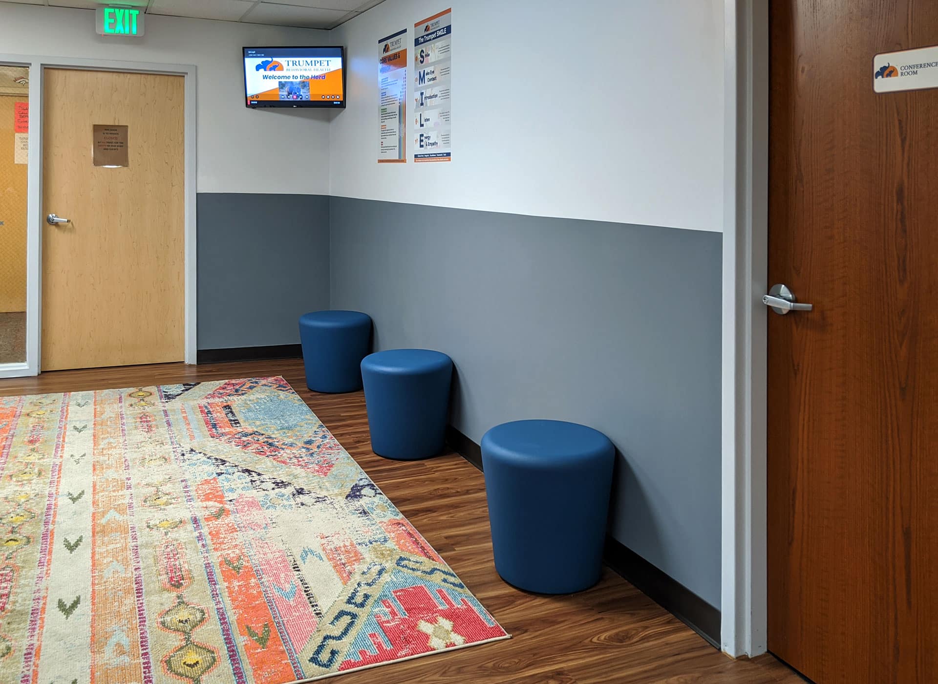 The hallway in BlueSprig autism centers features a comfortable rug and small blue stools.