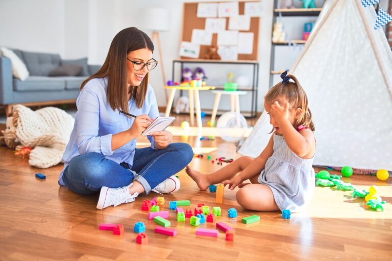 A therapist and child play games on the floor during in-home therapy.
