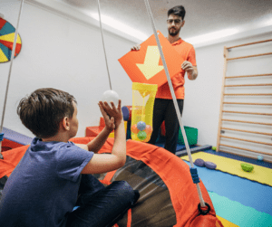 A BCBA plays a hoop shooting game with an early intervention client