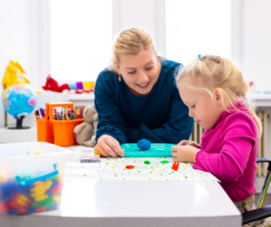 A BCBA works on a craft with an early intervention client