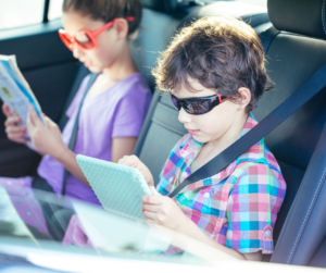 Two children read in the back seat of a car.