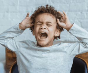 A child screams with their eyes closed