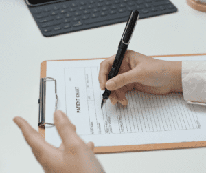Someone writes on a form attached to a clipboard