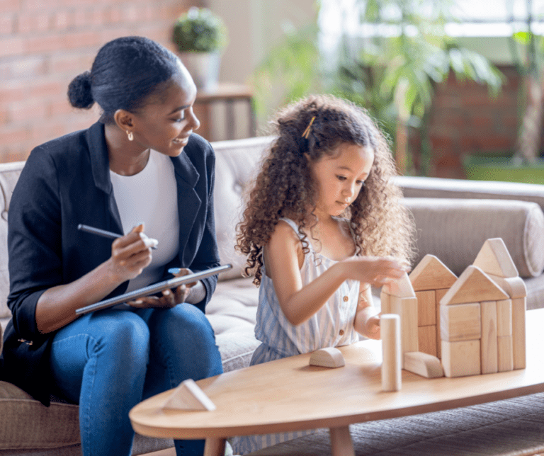 An RBT writes on a clipboard while watching a child play with blocks