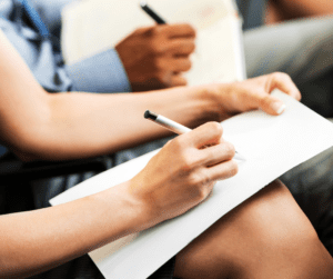 Hand holds a pen and writes on clipboard