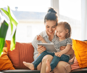 Parent and child look at tablet on couch