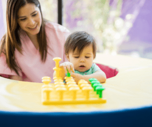 A therapist plays with a yellow toy with an infant boy.