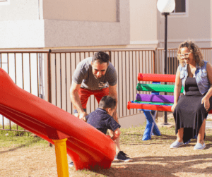 A man catches a child at the bottom of a slide