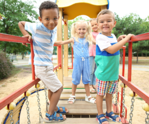 Kids stand on playground equipment.
