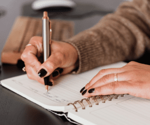 Hands writing in notebook with pen