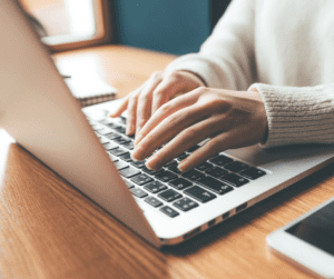 Hands type on a laptop computer.