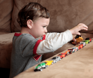 Toddler boy lines up toy cars.