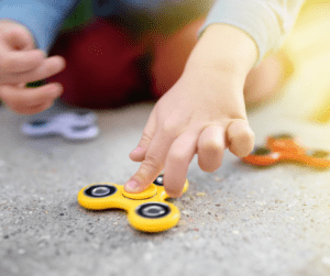 Child touches a yellow fidget spinner sensory toy.