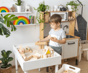 Toddler boy plays with blocks at a white table.